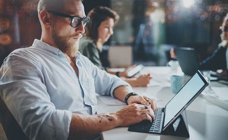 How To Write A Resignation Letter: Step-By-Step Guide Evinex Corporation | Staffing Agency a man typing on a computer tablet