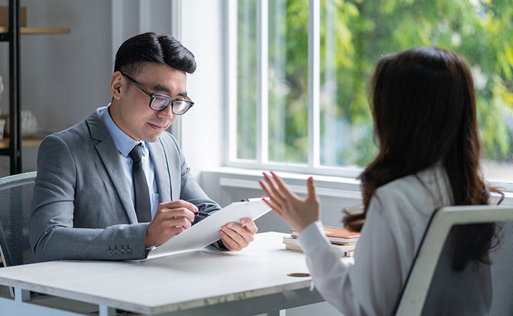 How To Impress In An Interview: Tips To Stand Out Evinex Corporation | Staffing Agency a man wearing a suit talking to woman that is raising her hands