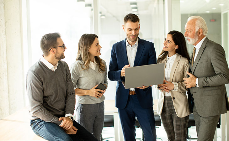 a man with a laptop is presenting to a smiling team