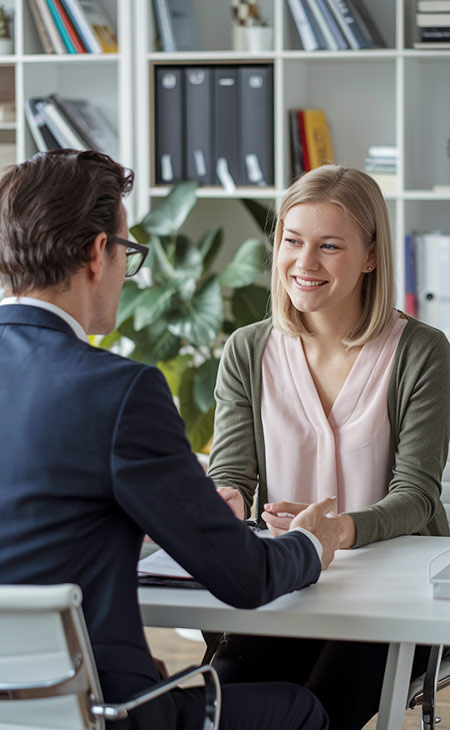 How To Impress In An Interview: Tips To Stand Out Evinex Corporation | Staffing Agency a smiling woman talking to a man in a suit in an office