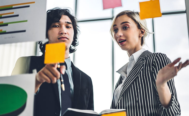 How To Lead A Team: Strategies For Effective Leadership Evinex Corporation | Staffing Agency a surprised woman talking to a man pointing to a post it