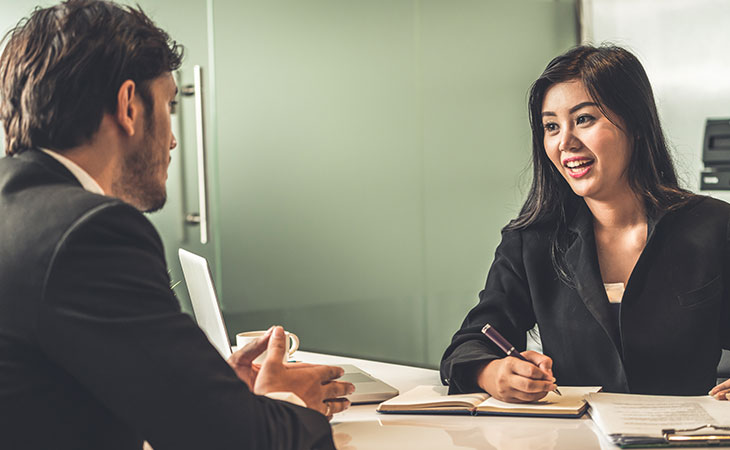 a woman is smiling in a meeting with a man