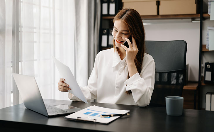 a woman talking on the phone looking at papers
