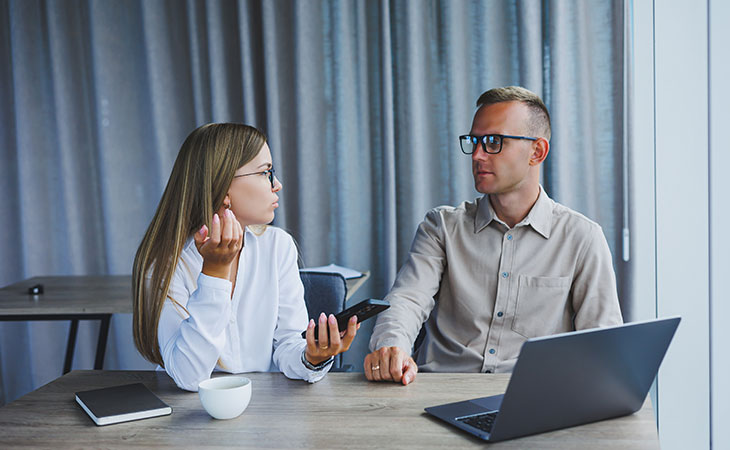 a woman with a phone and laptop is having a conversation