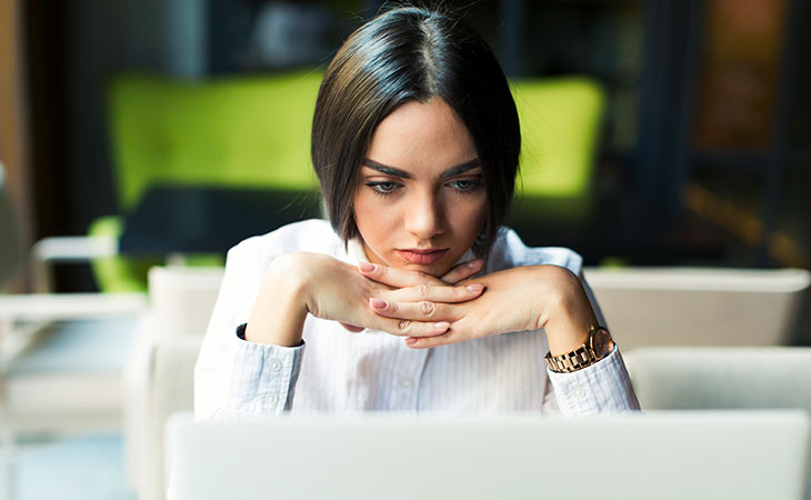 How To Write A Resignation Letter: Step-By-Step Guide Evinex Corporation | Staffing Agency a woman with her hands in her chin looking at laptop