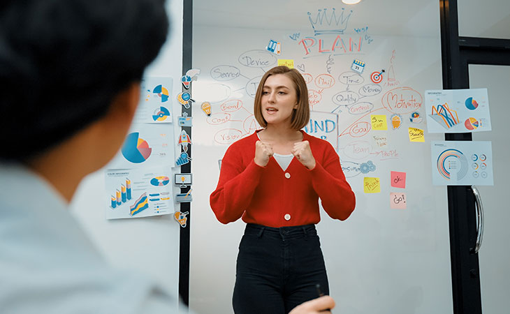 How To Lead A Team: Strategies For Effective Leadership Evinex Corporation | Staffing Agency a woman with her hands raised speaking