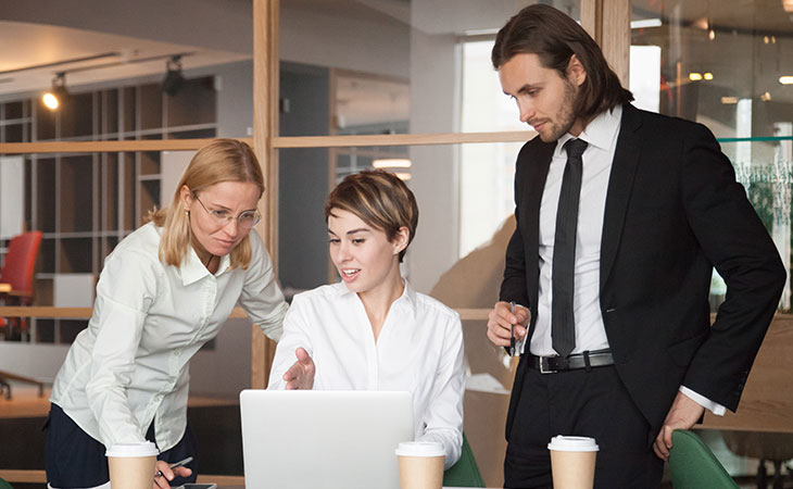 three people with a laptop are engaged in a project discussion