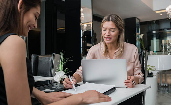 Interview Cheat Sheet: Essential Tips To Ace Your Interview Evinex Corporation | Staffing Agency two women signing papers and using a laptop
